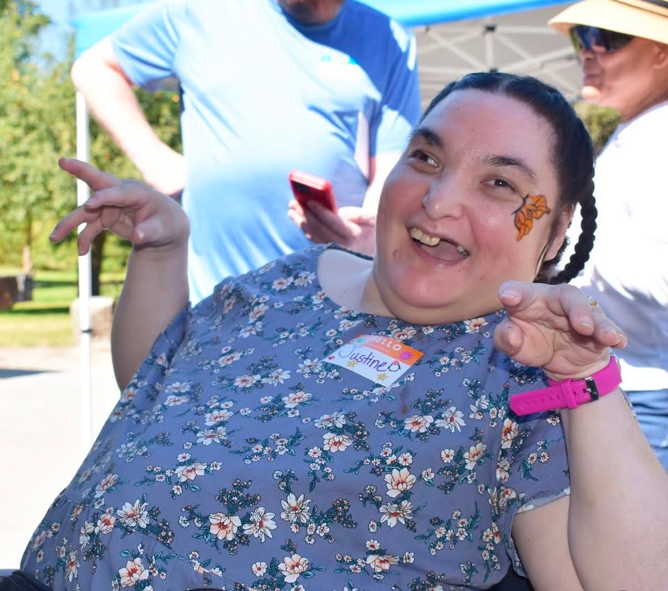 Justine smiling with a butterfly painted on her cheek at an outdoor community event